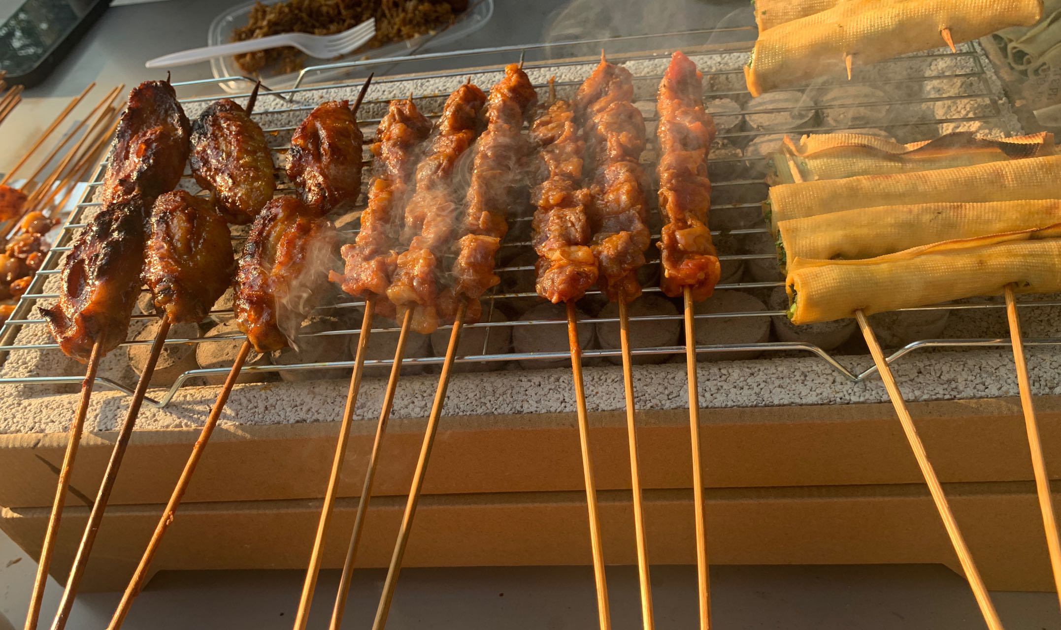 Skewers and vegetables cooking over charcoal